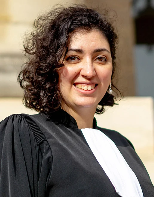 Femme avocate souriante aux cheveux bouclés, portant une robe noire et un jabot blanc à Paris 17eme arrondissement en Ile-de-France 75