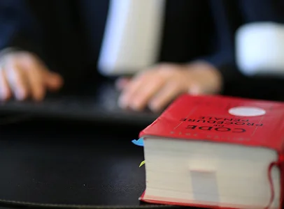 Livre de droit pénal sur un bureau, personne tapant au clavier en arrière-plan flou à Paris 17eme arrondissement en Ile-de-France 75
