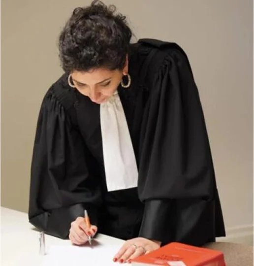 Femme avocate en robe noire et jabot blanc, écrivant à un bureau à Paris dans le 17eme arrondissement en Ile-de-France 75