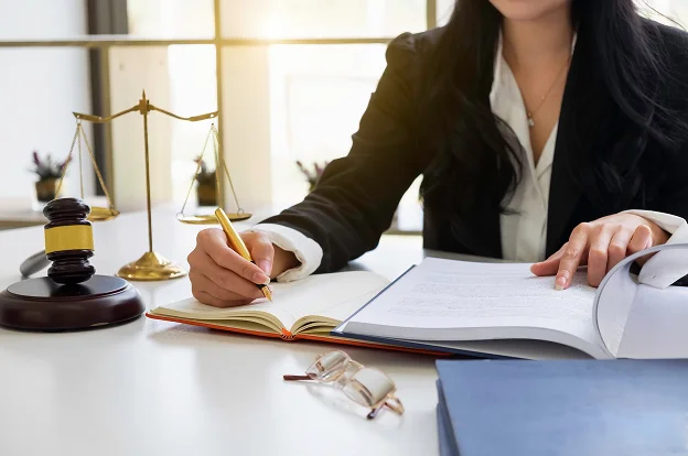 Avocate rédigeant des notes tout en lisant un document, avec balance de la justice à Paris 17eme arrondissement en Ile-de-France 75