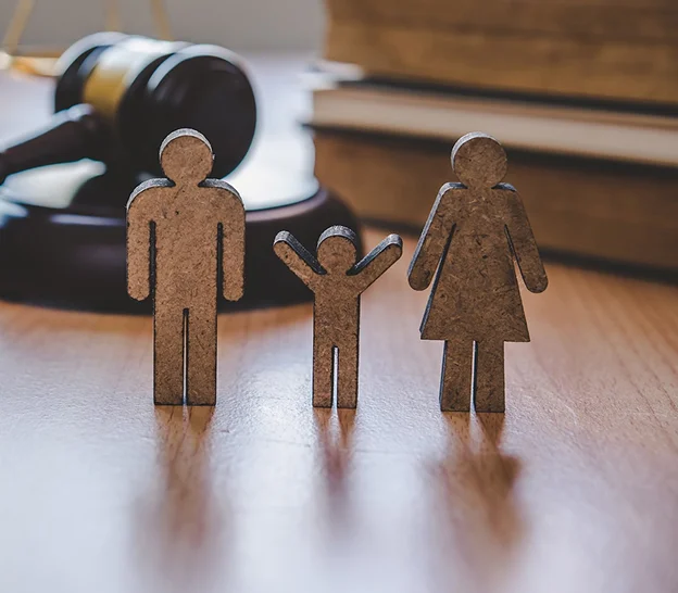 Figurines en bois d'une famille (homme, enfant, femme) devant un marteau de juge et des livres à Paris 17eme arrondissement en Ile-de-France 75